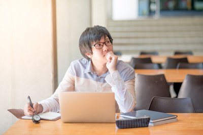 年轻的亚洲人工作与笔记本电脑在大学
