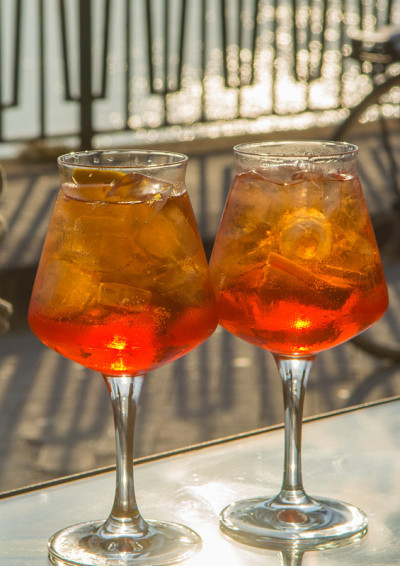 侍者准备了Aperol Sprits夏季鸡尾酒Aperol, prosecco，冰块和橙子在葡萄酒杯