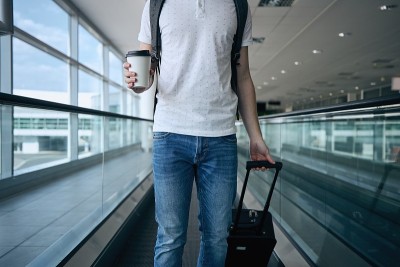 一名男子拿着纸杯在机场候机楼走来走去