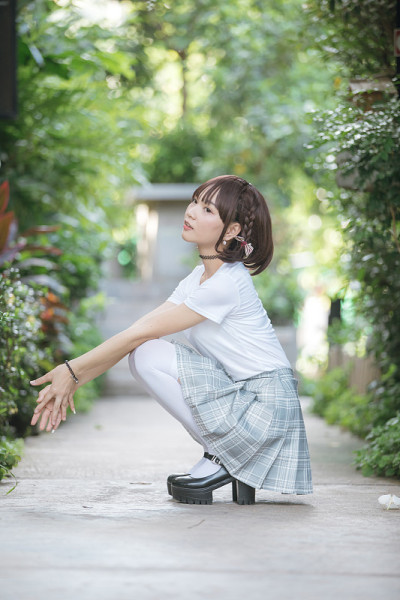 亚洲女孩的肖像与白色衬衫和裙子坐在户外自然复古电影风格
