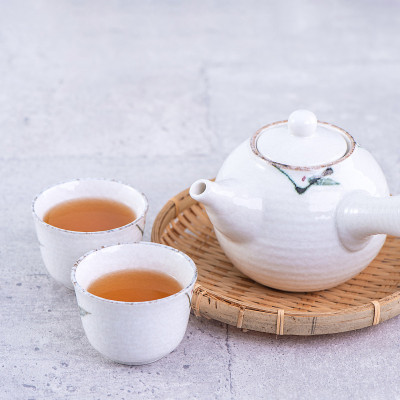 热茶在白色茶壶和杯子上筛过亮灰色水泥背景，特写，复制空间设计理念。