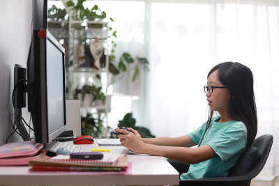 十几岁的亚洲女孩坐在客厅玩电子游戏