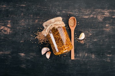 谷物芥末。香料在深色的木制背景上。前视图。为你的文本复制空间。