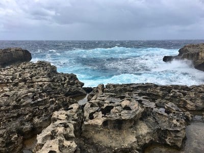 岩石海岸与多云的天空和海浪在海上