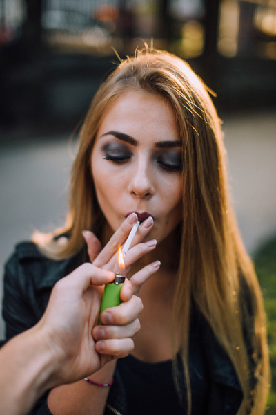 日落背景上吸烟的女人