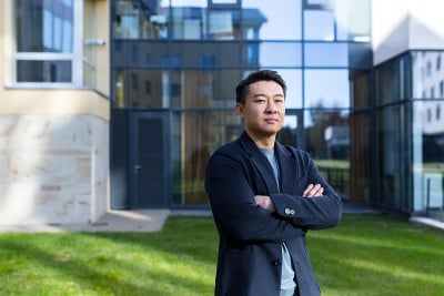 肖像英俊的亚洲人大学学院教师，商人，科学家或教育家。站在现代办公中心或校园背景，双臂交叉站在户外，对
