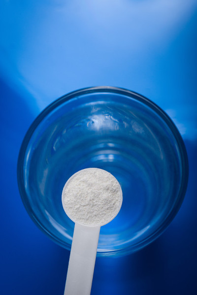 运动补充剂，肌酸，hmb, bcaa，氨基酸或维生素-测量粉与一杯水。运动营养的概念。