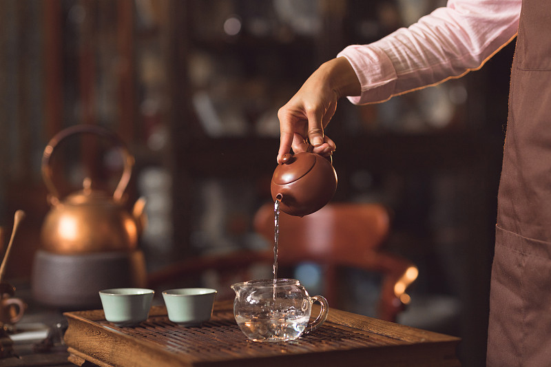 女人的手在室内倒茶