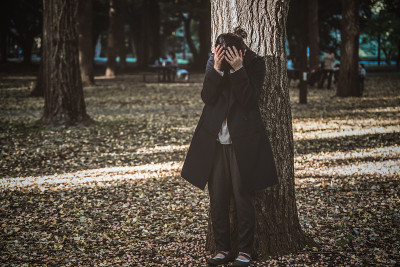 沮丧的女人倚在树上