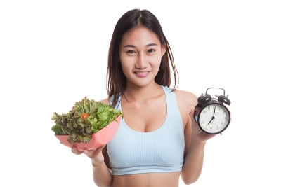 美丽的亚洲健康女孩，带着时钟和沙拉。