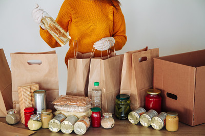 妇女在医疗手套包装食品捐赠