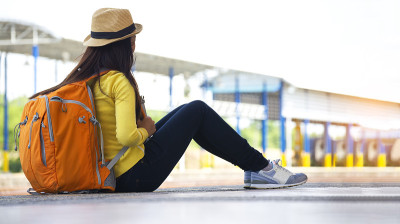 年轻的亚洲妇女微笑的旅行者女孩走着，在站台上等待火车