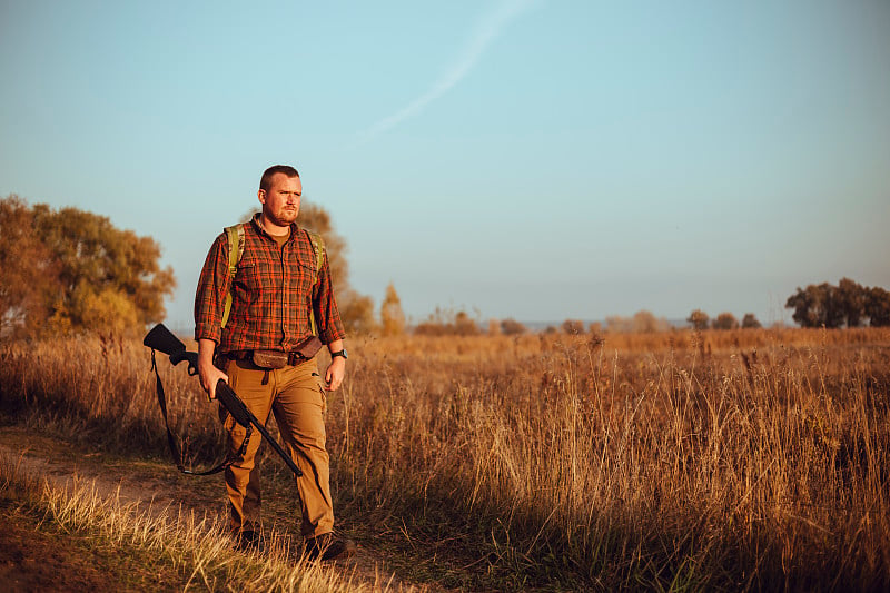 Strong young hunter with red beard holding his gun