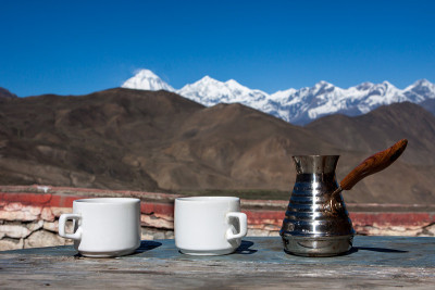 喝着咖啡，欣赏迷人的山景。美丽的喜马拉雅山景观，咖啡杯和塞维。在雪景背景下喝咖啡。