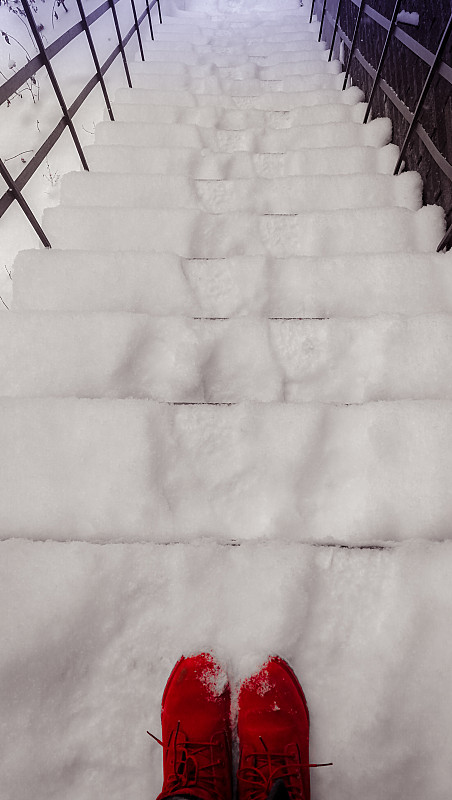 被雪覆盖的楼梯上的红靴子