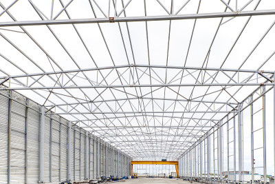 正在建设的工业钢结构建筑和起重机的视图。许多结构钢的形状都是具有特定截面的细长梁。