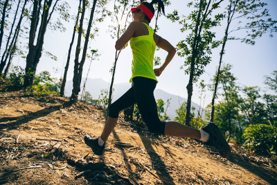 年轻女子trail runner在日出热带森林跑步
