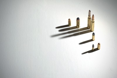 几颗子弹站在白色的地面上，上面有长长的、黑暗的、引人注目的影子