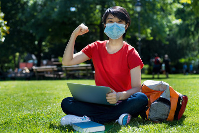 在大学校园里，戴着口罩和电脑的东亚男同学在欢呼