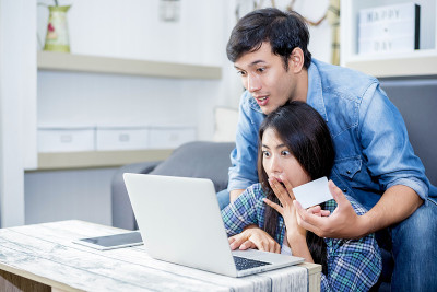 情人在使用笔记本电脑时会感到惊讶。家庭理念、情侣理念、科技理念
