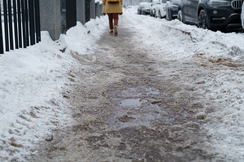 特写技术盐颗粒在结冰的人行道表面在冬季，用于融化冰雪。