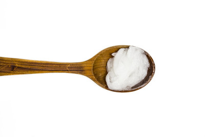 纯初榨椰子油或椰子干油是一种可食用的油。在棕色木勺孤立在白色。代替商店的面霜概念。