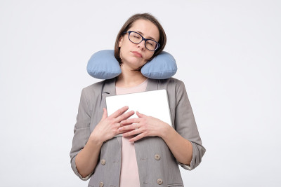 白种成年女人戴着眼镜，在度假旅行中枕着旅行枕