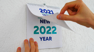 在2021年挂历12月页和2022年新挂历标题页之间，男性的手在翻