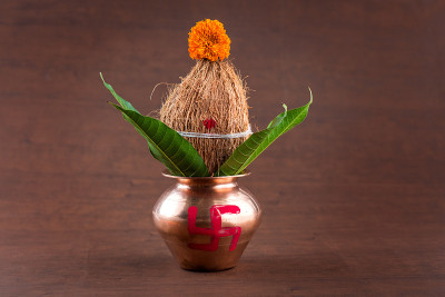 铜kalash椰子和芒果叶与花卉装饰在木背景。这在印度教礼拜中很重要。