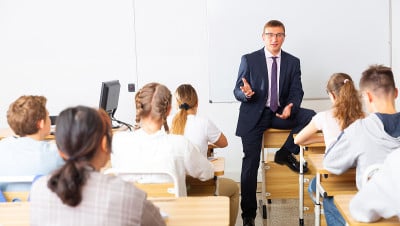 一个带着笔记本的老师正在教室里给学生们讲有趣的课