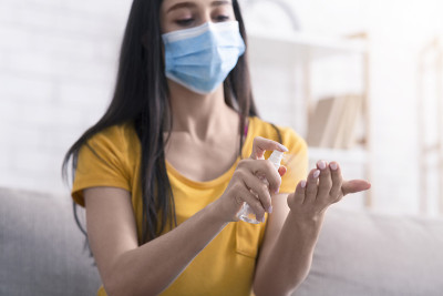 冠状病毒预防。小女孩戴医用口罩，在家用洗手液洗手