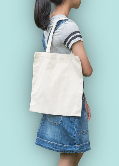 帆布手提袋模型棉织物纹理在女孩的肩膀(裁剪路径)在白色奶油色孤立在蓝色背景