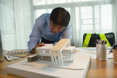 与现代箱式住宅模型一起工作的建筑师-设计师，在未来启动前思考建筑概念和建设项目。