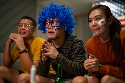 一群亚洲人朋友在家里一起看全国体育比赛和欢呼。
