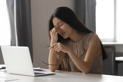 劳累过度的亚洲商务女性持有眼镜感觉眼睛疲劳