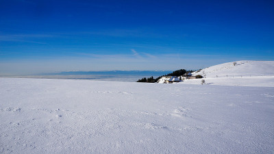 一个农场前的冬山和白雪皑皑的田野，后面是高山