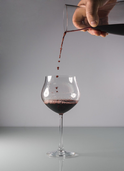 将红酒从上方倒入中性背景的大气球杯，瞬间凝固。