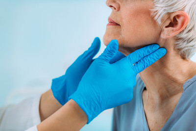 甲状腺控制。内分泌科医生在诊所检查老年妇女。