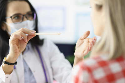女医生用木铲特写检查病人的喉咙