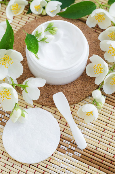 白色面膜(面霜、发膜、体乳、洗面奶)，小白色罐子，棉垫和茉莉花。自然的皮肤和头发概念。俯视图，复制空