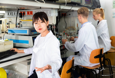 年轻的中国女学生在实验室的设备附近摆姿势