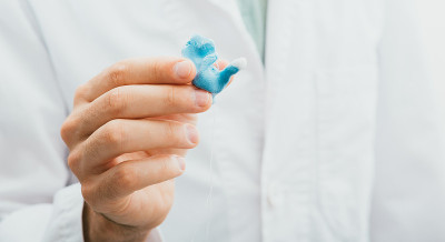 医生拿着他的手为他的病人塑造了一个单独的助听器耳模，特写。听力解决方案