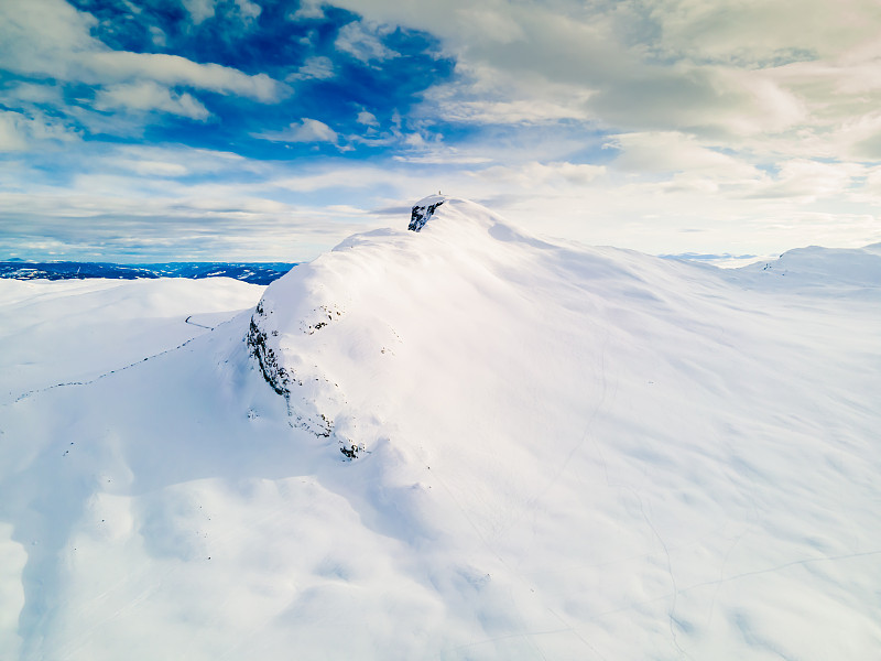 雪山山顶的全景与云和蓝天。挪威的比提霍恩山。