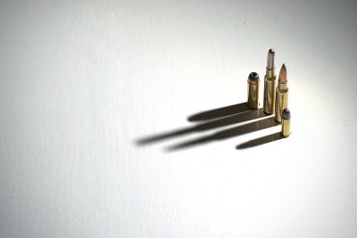 几颗子弹站在白色的地面上，上面有长长的、黑暗的、引人注目的影子