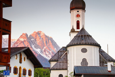 在红色晨光中陡峭的Waxenstein和Zugspitze山峰上的天主教教堂圣马丁和房屋，德国拜仁欧