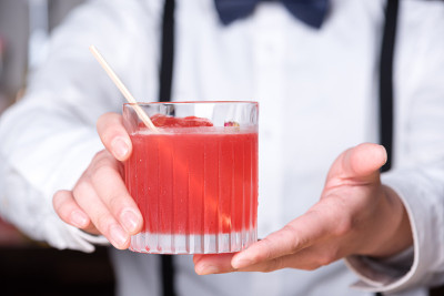 酒保双手递上红色的鸡尾酒