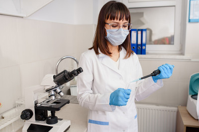年轻的女医生实验室助理正在医学显微镜旁使用微管试管。