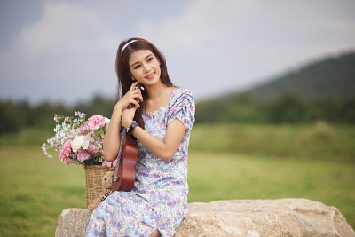 美丽的亚洲女音乐家在自然背景。