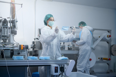 现代工厂生产外科口罩的工人，新冠病毒防护和医疗理念。