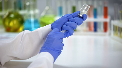 实验室科学家用注射器中的液体稀释药粉，接种疫苗